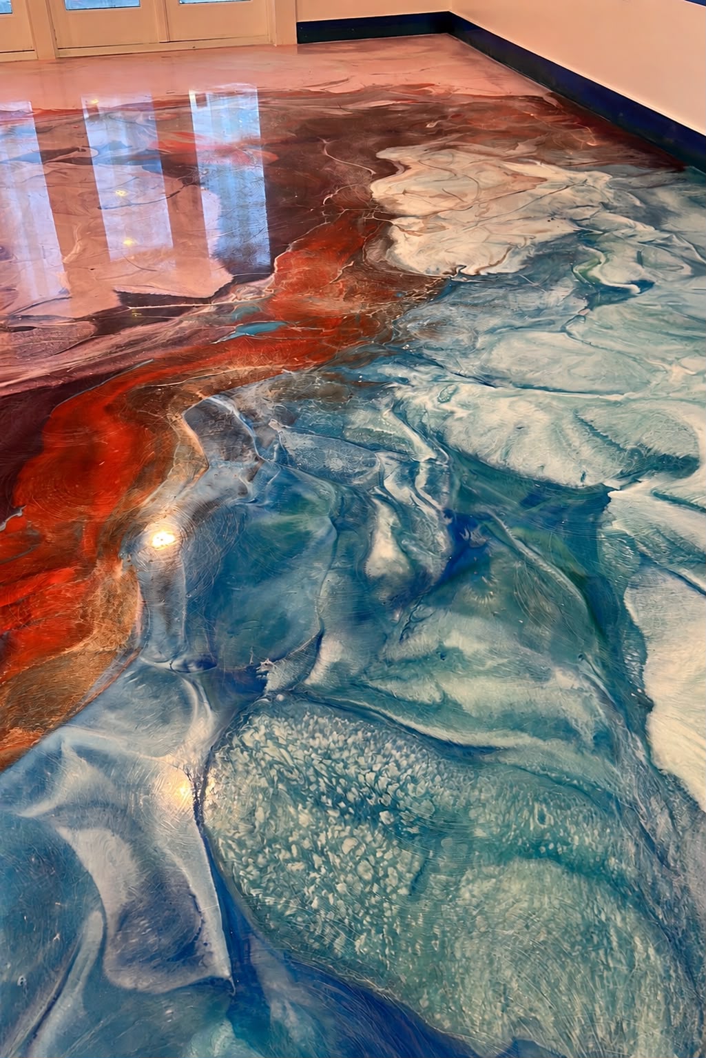 Epoxy floor with crimson lava river meeting blue surf